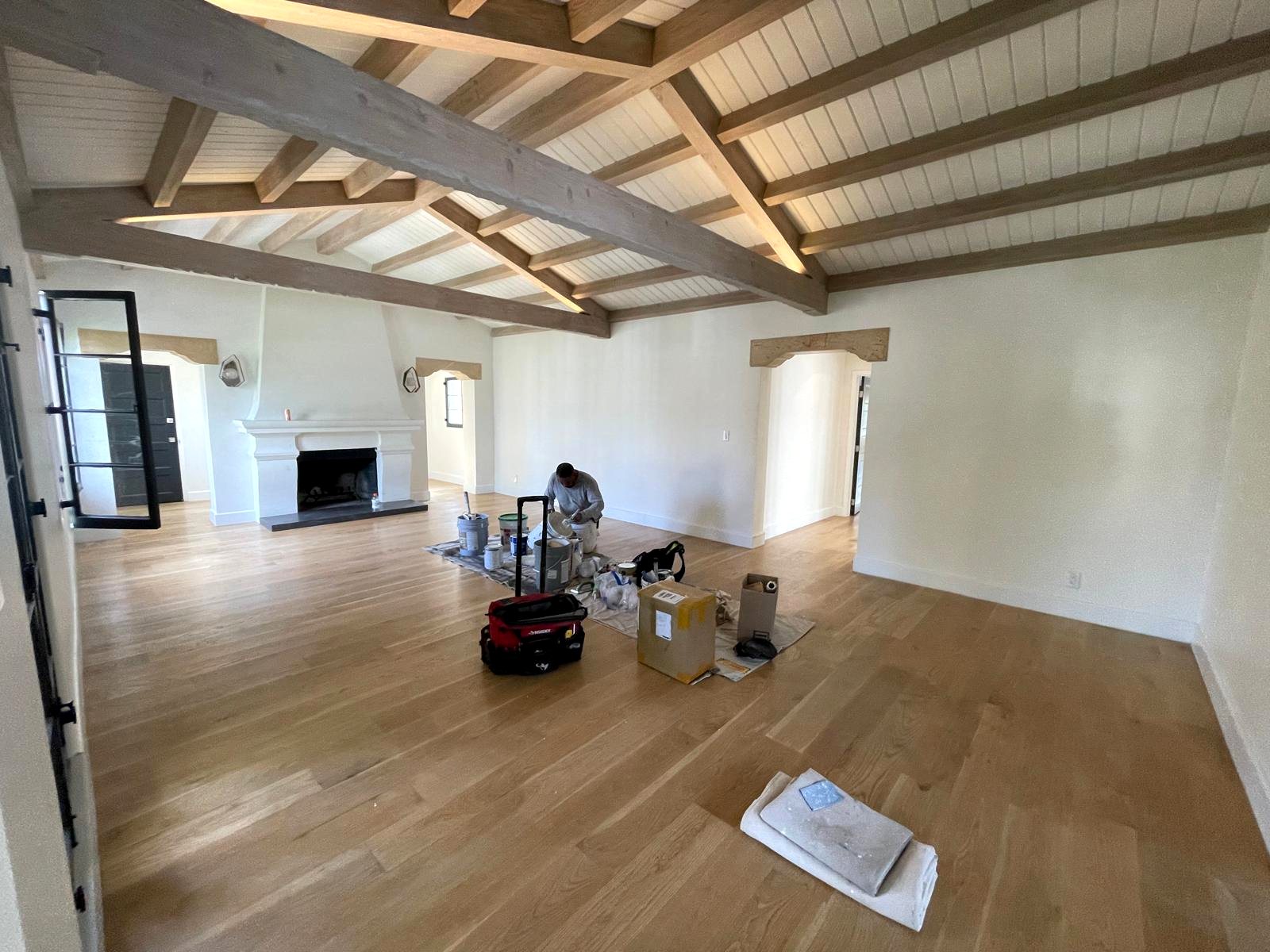 Fully remodeled living room with vaulted wood beam ceiling and custom fireplace — Los Angeles
