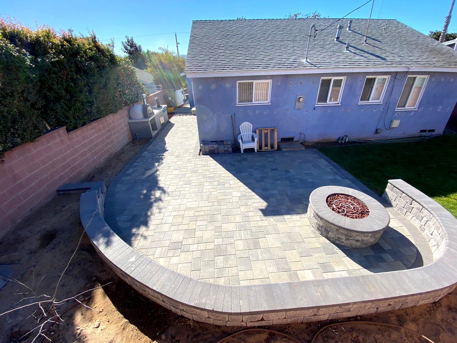 Paver patio with built-in fire pit and outdoor kitchen with pizza oven — Los Angeles